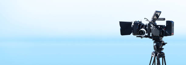 istock Digital movie camera on blue studio background with copy space. Broadcast, movie production or television banner 1402596112