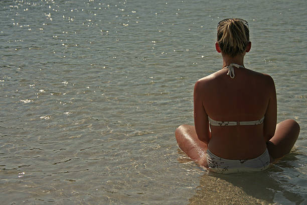 young woman is sitting on the beach and mmeditate stock photo