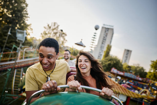istock Happy mixed-race couple having fun while riding on rollercoaster at amusement park. 1402597428