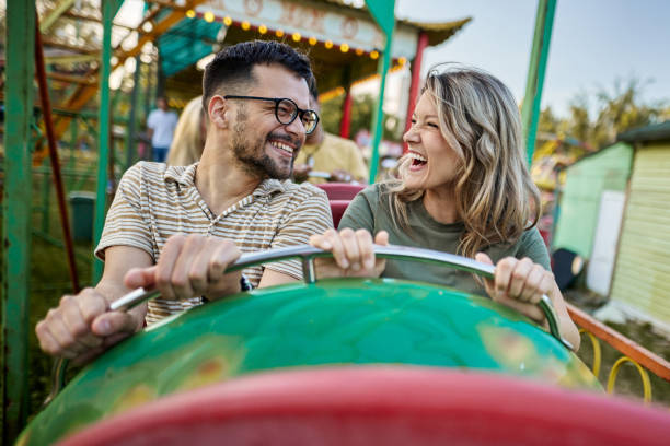 istock Young happy couple talking during rollercoaster ride at amusement park. 1402597479