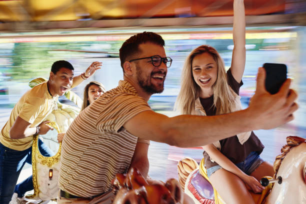 istock Happy friends taking a selfie during carousel ride at amusement park. 1402597590