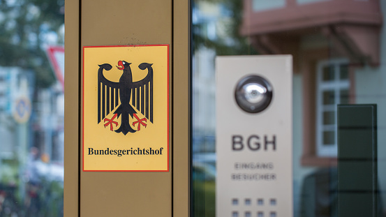 Karlsruhe, Germany - Aug 28, 2021: Sign Bundesgerichtshof (german federal court of justice) at the entrance of the main building. In the foreground the (blurry) abbreviation BGH.