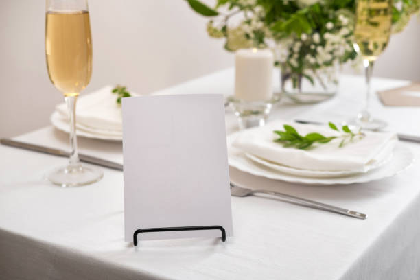 istock Mockup white blank space card for table number or menu. Wedding teble decoration with white flowers, glasses and white napkins. Elegantly decorated table at a wedding reception. Festive table setting. The wedding decor. 1402599409