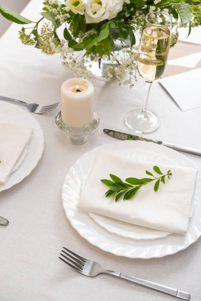 istock Wedding table decoration with white flowers, glasses and white napkins. Elegantly decorated table at a wedding reception. Festive table setting. The wedding decor. 1402599956
