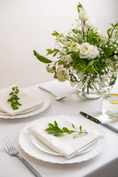 istock Wedding table decoration with white flowers, glasses and white napkins. Elegantly decorated table at a wedding reception. Festive table setting. The wedding decor. 1402600029