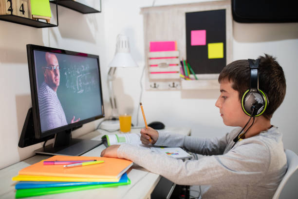 Distance learning, a boy in headphones sits at a table at home. The concept of online education, home education, technology, school stock photo