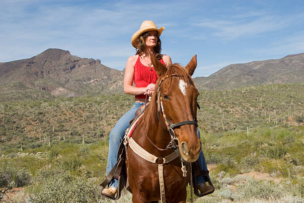 A close-up of a beautiful cowgirl gazing off into the distance aboard her faithful steed. Arizona desert background.