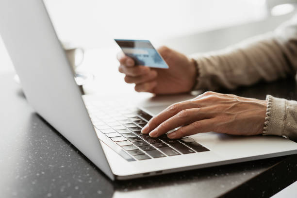 istock Payment online. Young man using laptop with credit card at home 1402602835