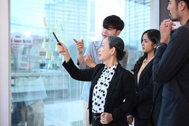istock Diverse business people brainstorming and sharing creative ideas throughs colorful sticky notes on glass window. 1402603225