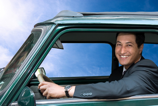 Smiling young man sitting in a green car