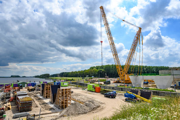 istock Mobile cranes at a construction site hauling new bridge sections over a waterway 1402605800