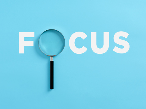The word focus with a magnifying glass. Focusing on a target in business or education concept.
