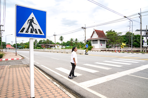 Asian man looks to vehicle on the road, he waits for sure to  across crosswalk to the other side, Thailand.