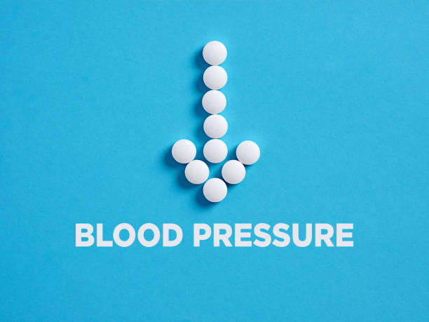 Round white medical pills in arrow shape pointing to the word blood pressure. Reducing blood pressure treatment Round white medical pills in arrow shape pointing to the word blood pressure. Reducing blood pressure treatment concept. blood pressure medication stock pictures, royalty-free photos & images