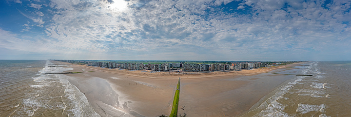 Drone panorama over the beach of the Belgian coastal town of Middelkerke at low tide with breakwaters during the day in summer