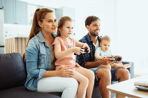 Parents at home with two children, playing video games