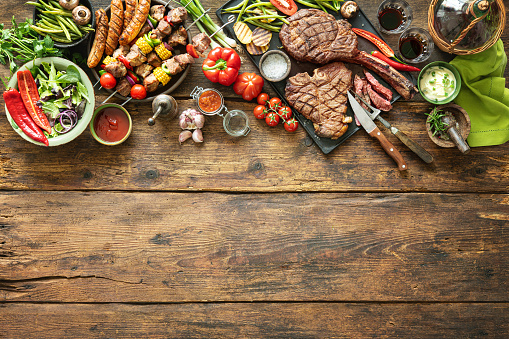 Grilled meats and vegetables on rustic timber picnic table