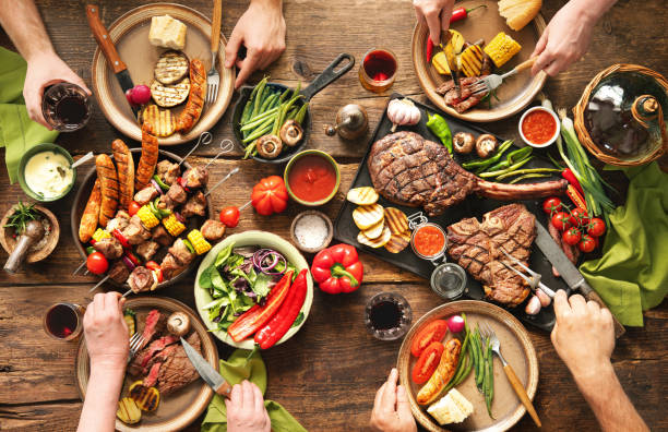 Friends having a barbecue party Friends having a barbecue party. Group of people eating grilled meats and vegetables and drinking wine at rustic picnic table grilled stock pictures, royalty-free photos & images