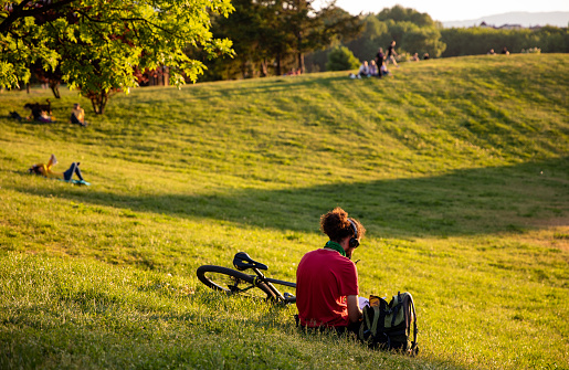 Young man relaxing after work on a fresh green meadow in a public park, Sofia, Bulgaria