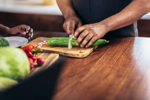 istock Close up shoot of black man holding sharp knife cutting cucumbers 1402614740