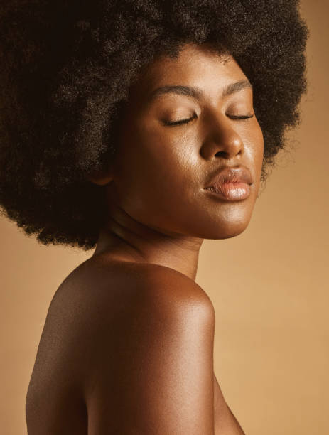 istock Confident African American woman with a natural afro posing against brown studio copyspace background. Young beautiful black female model looking trendy, powerful and sensual with smooth glowing skin 1402616450