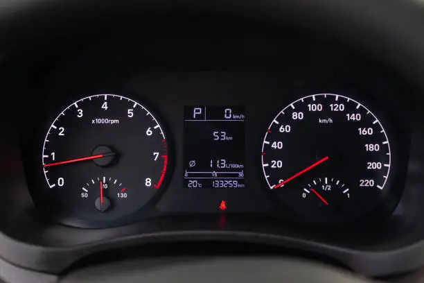 Photo of Modern car illuminated dashboard closeup. White arrows on Speedometer