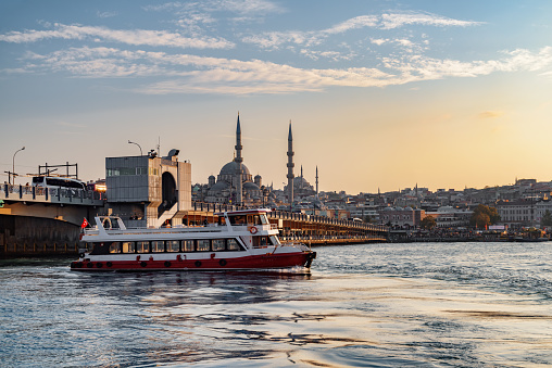 Scenic evening view of the Galata Bridge over the Golden Horn and the New Mosque (the Valide Sultan Mosque). Awesome Istanbul skyline.