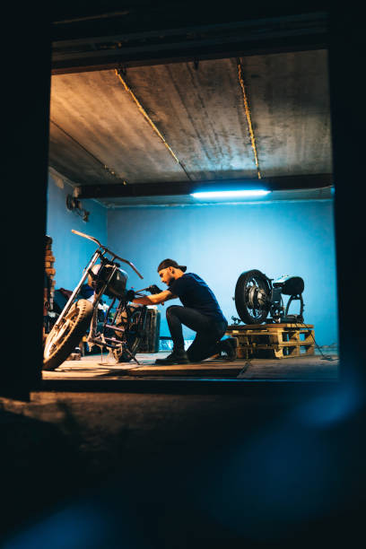 Motorcycle repair. Young man repairing motorbike in garage. stock photo