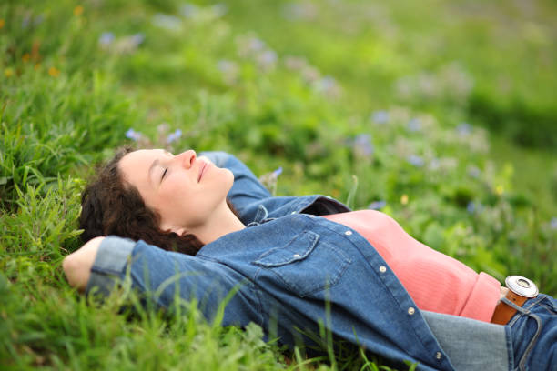 istock Woman resting and relaxing lying on the grass in a park 1402619157