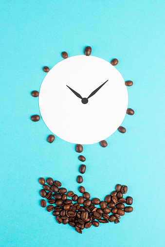 Cup of coffee with coffee beans and an alarm clock