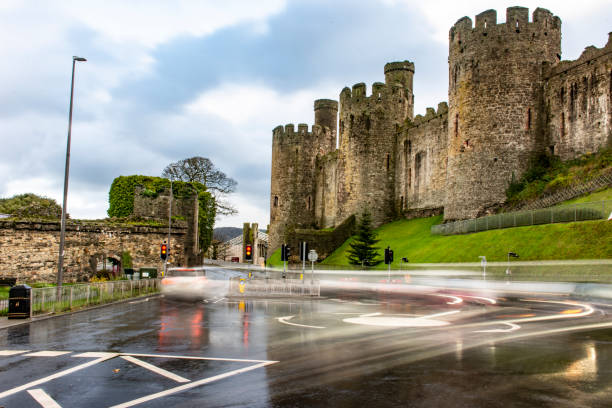 Conwy Castle Traffic with their lights on due to the rain at a roundabout blurred by a long exposure below Conwy Castle. conwy castle stock pictures, royalty-free photos & images
