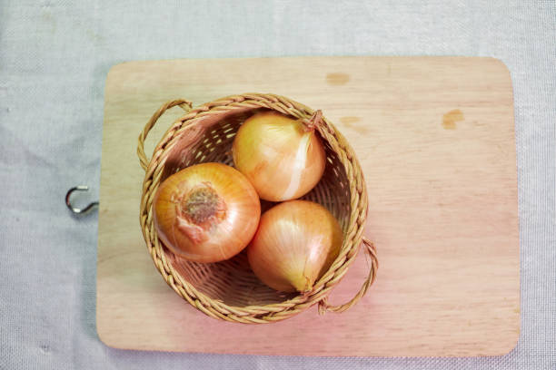 Fresh onion in a wicker basket with cutting board