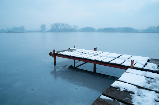 Snow on a pier on a frozen lake, winter view