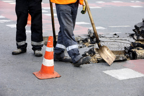 рабочие ремонтируют дорожное покрытие, человек с лопатой возле канализационного люка - scrap metal audio стоковые фото и изображения