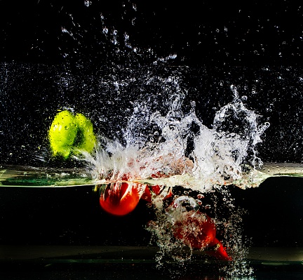 Fruits fall into the water on a black background