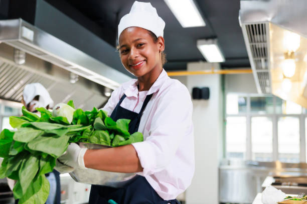 porträt junges teenager-mädchen kochschülerin. kochkurs. kulinarisches klassenzimmer. glückliche junge afrikanische studentinnen, die frisches gemüse zum kochen in der kochschule halten. - photography teaching fun one person stock-fotos und bilder