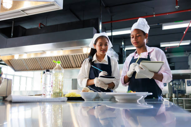 istock take note on book. Cooking class. culinary classroom. group of happy young woman multi-ethnic students are focusing on cooking lessons in a cooking school. 1402628362