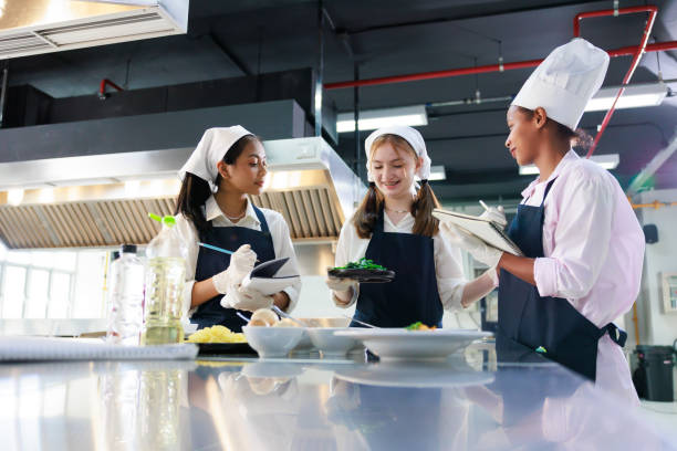 istock take note on book. Cooking class. culinary classroom. group of happy young woman multi-ethnic students are focusing on cooking lessons in a cooking school. 1402628393