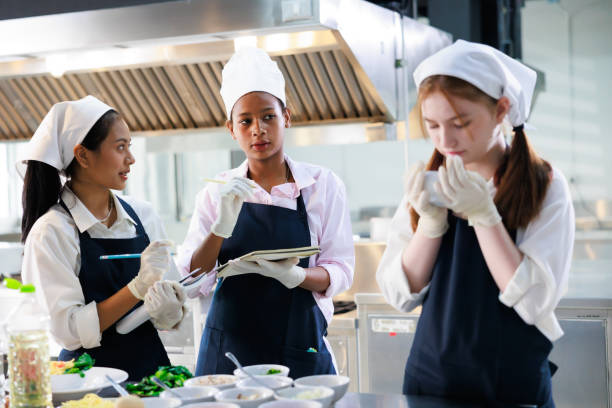 istock take note on book. Cooking class. culinary classroom. group of happy young woman multi-ethnic students are focusing on cooking lessons in a cooking school. 1402628434