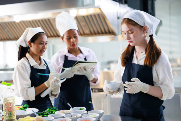 istock take note on book. Cooking class. culinary classroom. group of happy young woman multi-ethnic students are focusing on cooking lessons in a cooking school. 1402628435