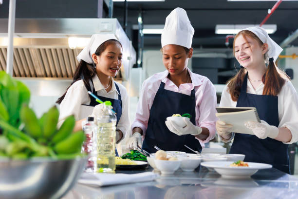 istock take note on book. Cooking class. culinary classroom. group of happy young woman multi-ethnic students are focusing on cooking lessons in a cooking school. 1402628436