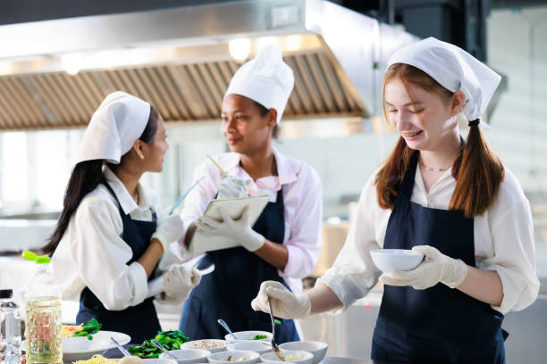 istock take note on book. Cooking class. culinary classroom. group of happy young woman multi-ethnic students are focusing on cooking lessons in a cooking school. 1402628490