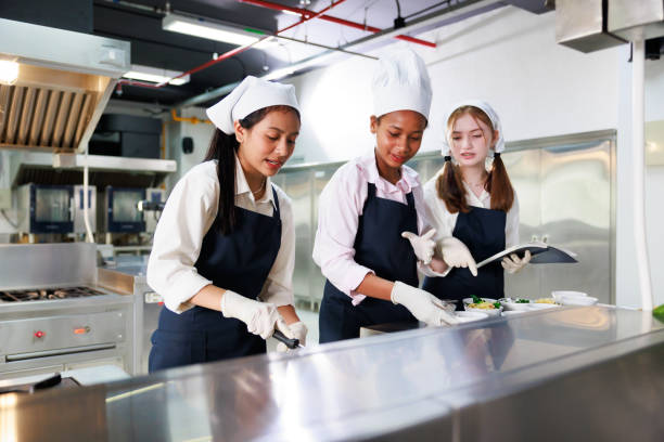 istock take note on book. Cooking class. culinary classroom. group of happy young woman multi-ethnic students are focusing on cooking lessons in a cooking school. 1402628558