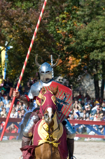 A red knight on horseback with javeline spear in hand ready to joust in a competition