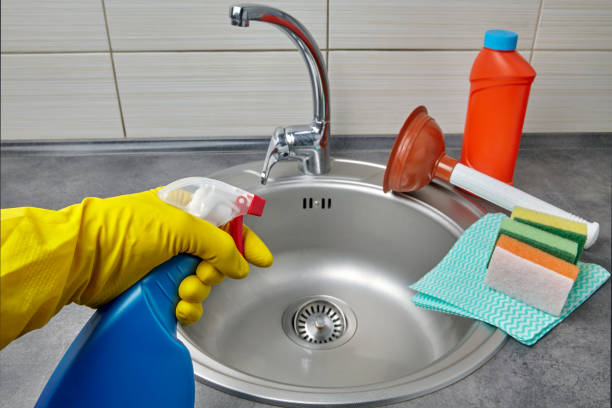 hands in yellow rubber gloves hold a spray bottle with cleaning agen - sink drain plumber domestic kitchen imagens e fotografias de stock