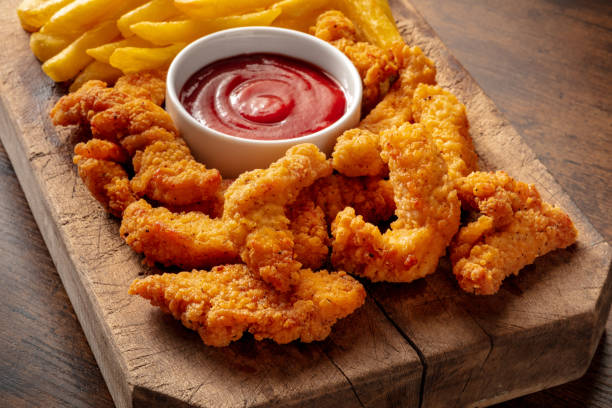 istock Battered chicken wedges, crispy nuggets, with a bbq sauce on a wooden table 1402633391