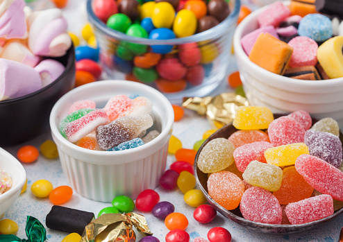 High angle view of an assortment of colorful jellybeans, lollipops, candies and marshmallows with copy space