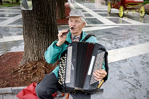 Old guy playing accordion and flute at the same time