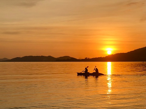 A couple enjoy kayaking in the Gulf of Thailand just before sunset