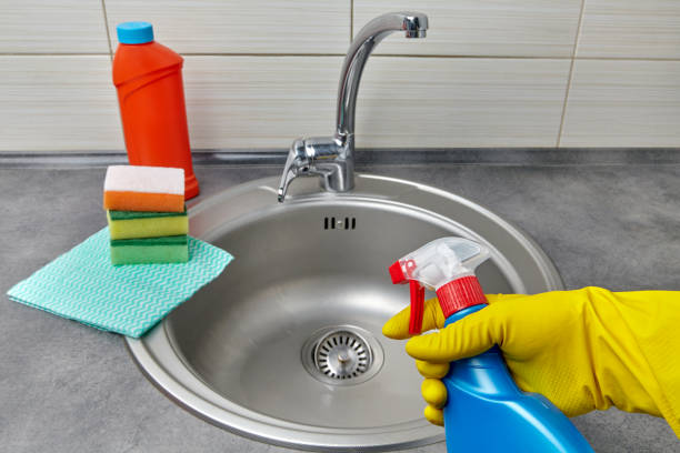 hands in yellow rubber gloves hold a spray bottle with cleaning agent - sink drain plumber domestic kitchen imagens e fotografias de stock